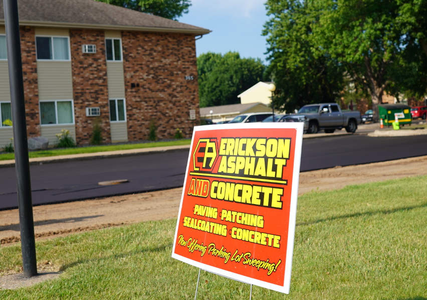 Close up of Erickson Asphalt & Concrete yard sign while project is being paved