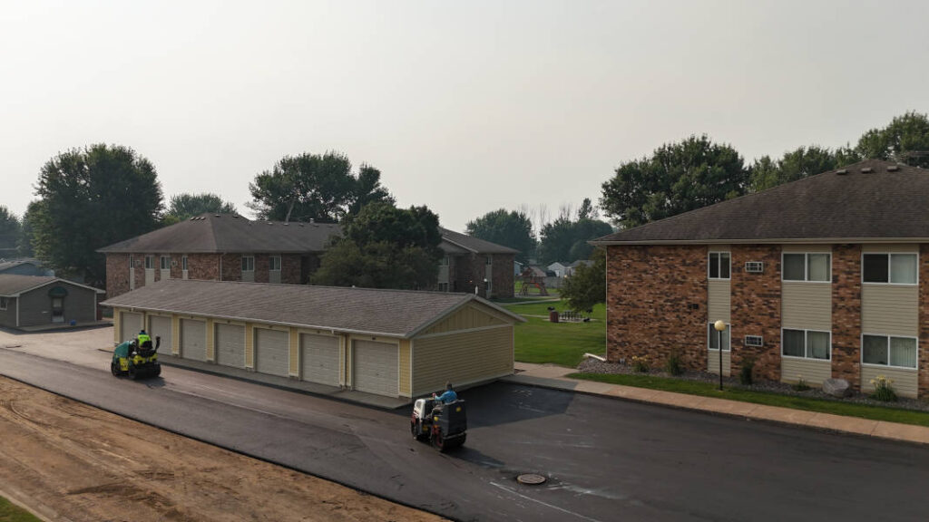 Aerial view rollers compacting asphalt in apartment building parking lot