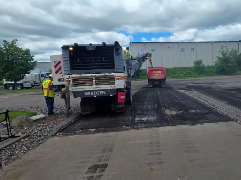 Asphalt milling machine loading asphalt millings into truck.